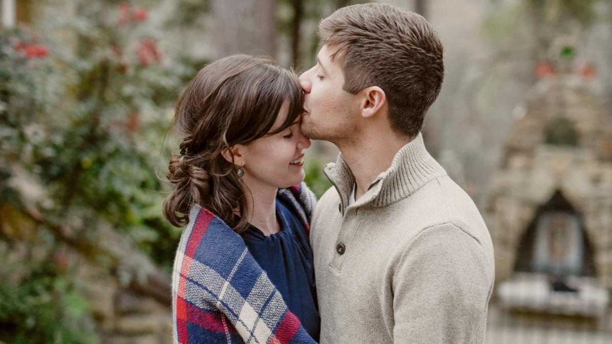 
man kissing woman with blanket on forehead standing near tree during daytime by Hannah Olinger
