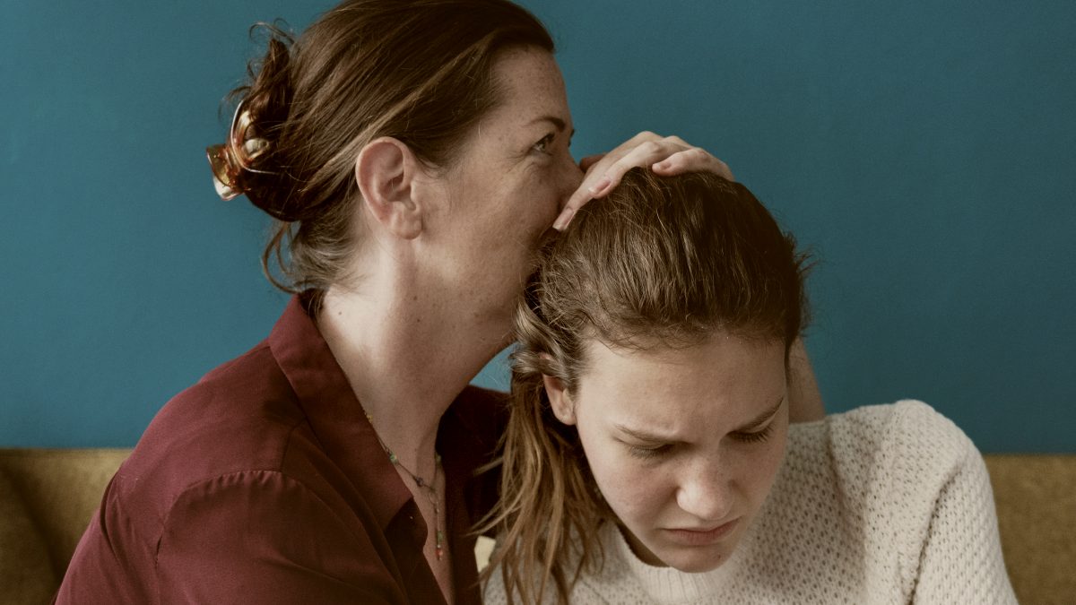 
Mother and teenage daughter having an argument with a blue wall behind them by curated lifestyle
