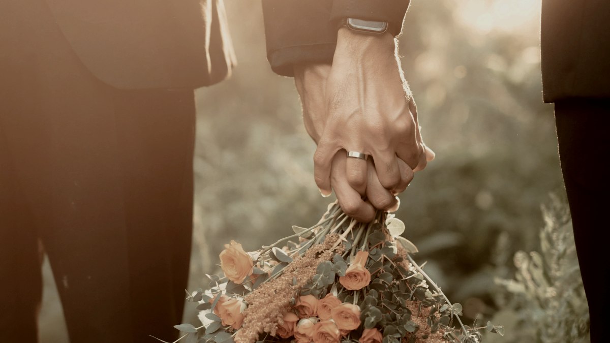 
newlywed-husbands-holding-hands-with-a-bouquet
