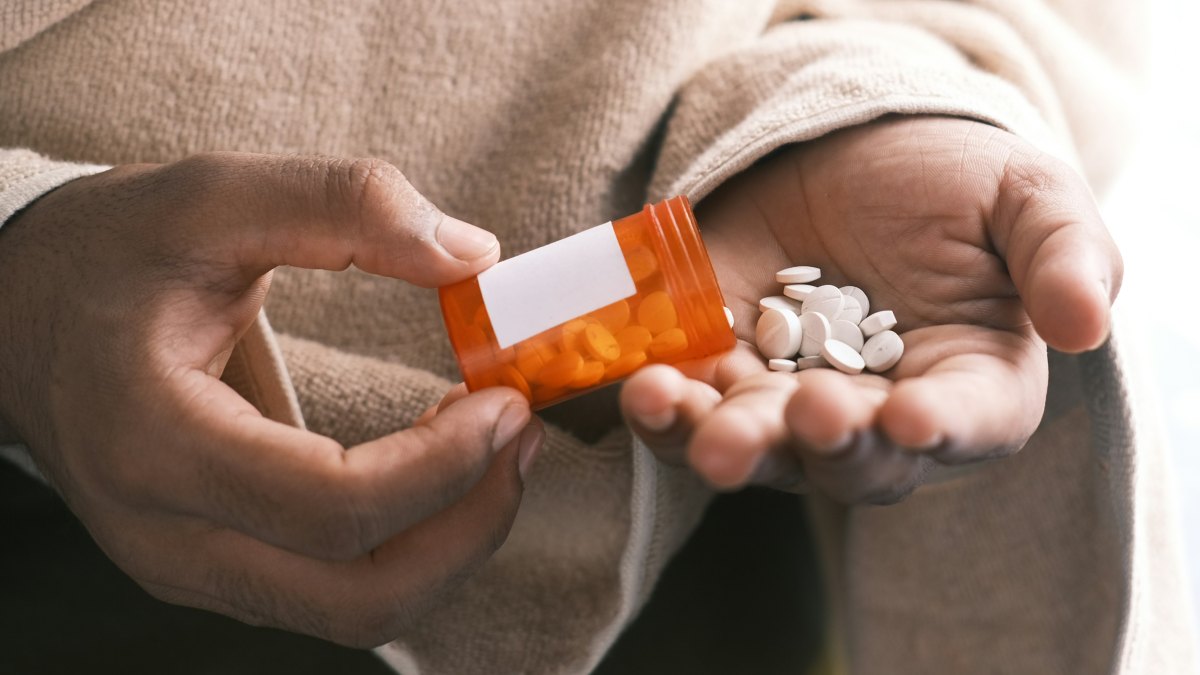 
orange and white plastic bottle pouring out pills into hand by Towfiqu barbhuiya
