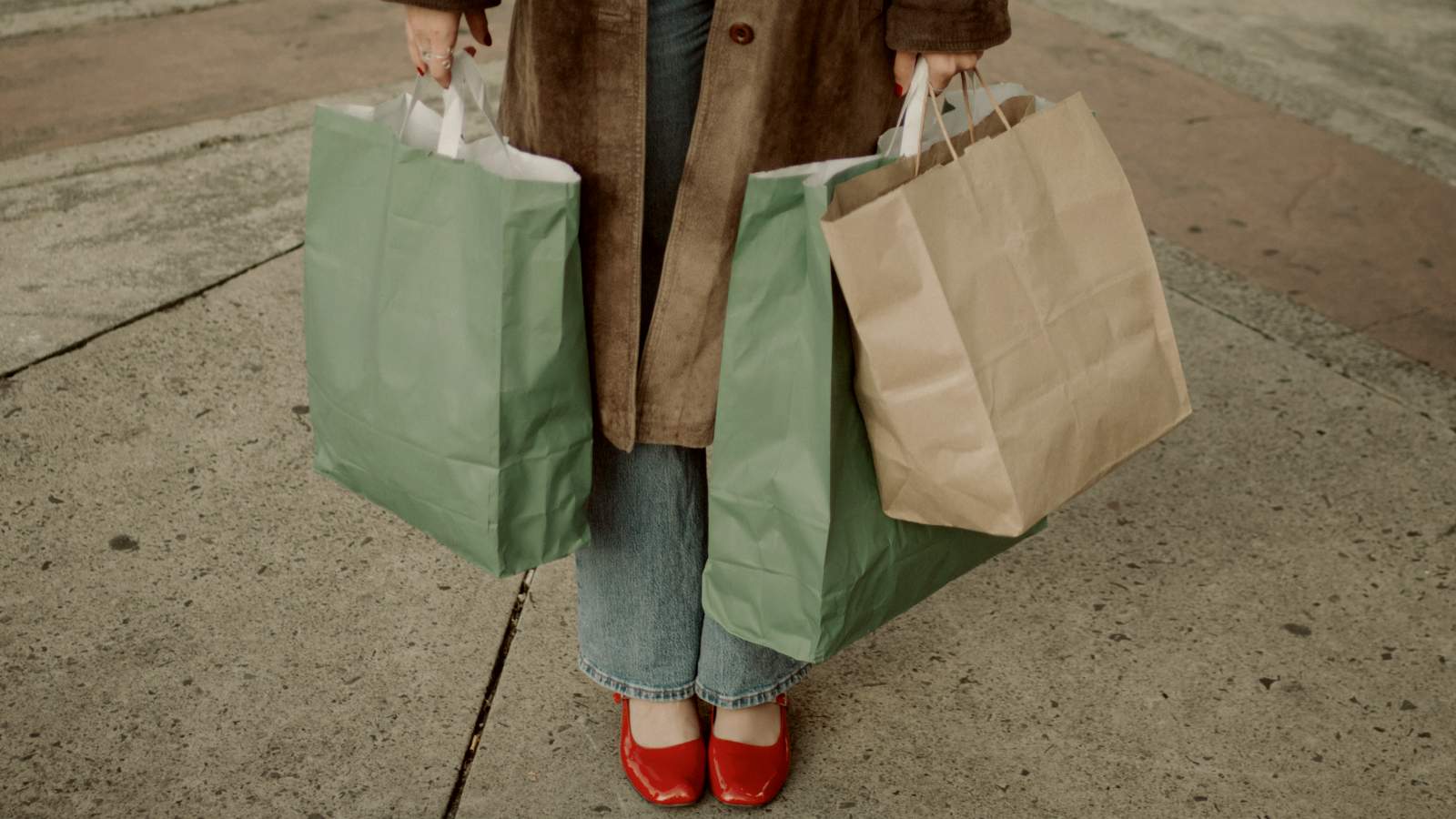 
Person holding many shopping bags with red shoes and brown coat by Ramsés Cervantes
