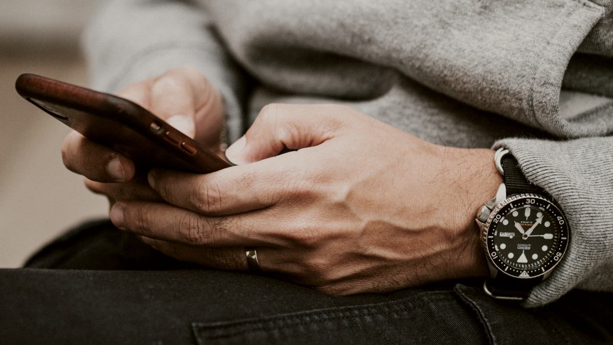 
person in grey sweater wearing black and silver chronograph watch holding a cell phone by Nathan Dumalo
