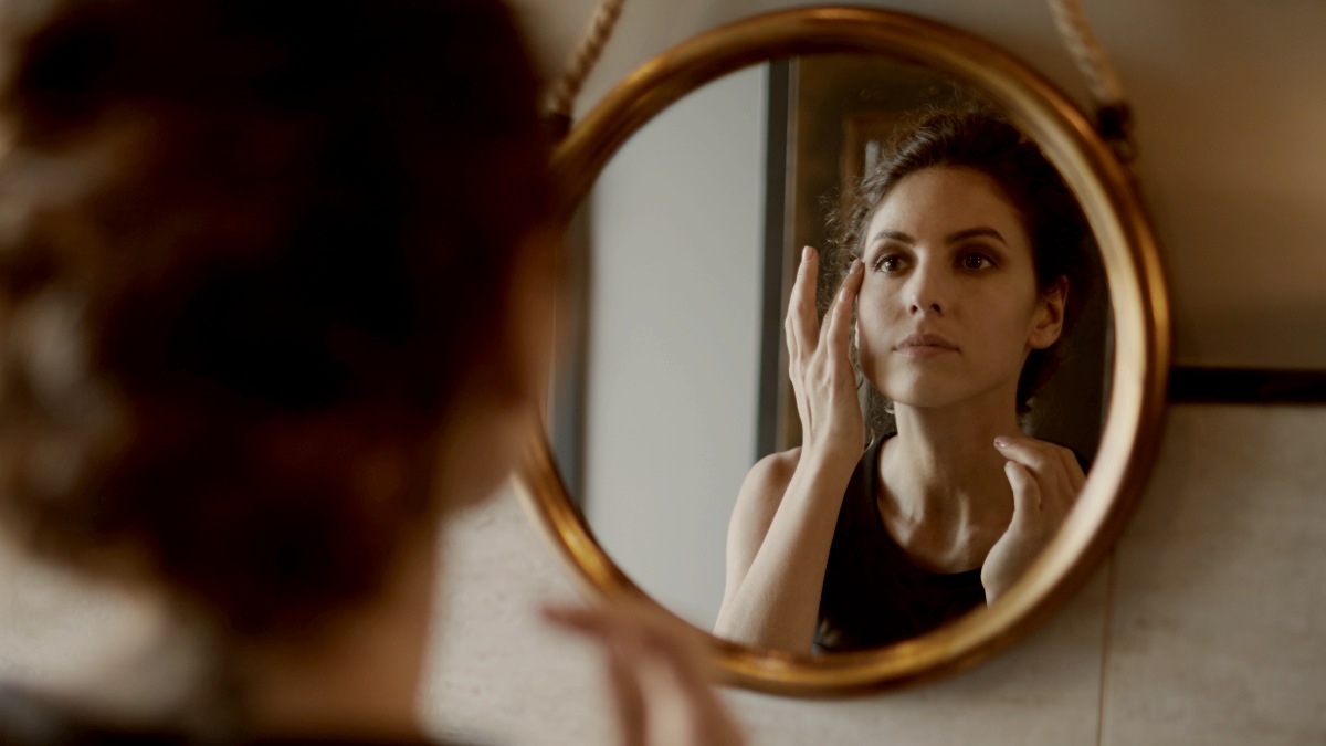 
Pretty young woman looking in mirror and refreshing her makeup in lavatory by Getty Images
