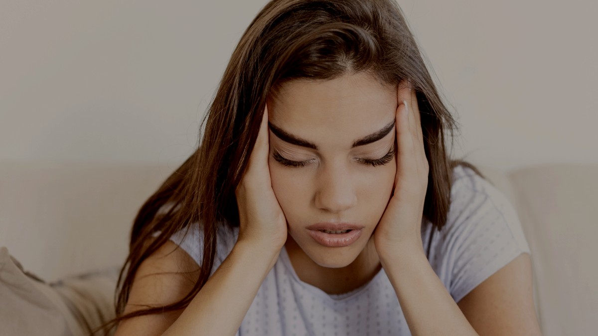 
Sad young woman sitting on a couch in the living room at home by getty images
