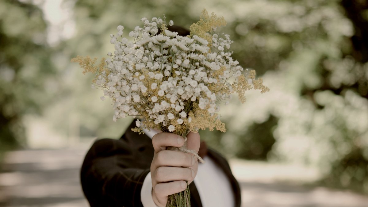 
selective focus photo of man wearing black suit jacket holding flower bouquet by Alex Padurariu
