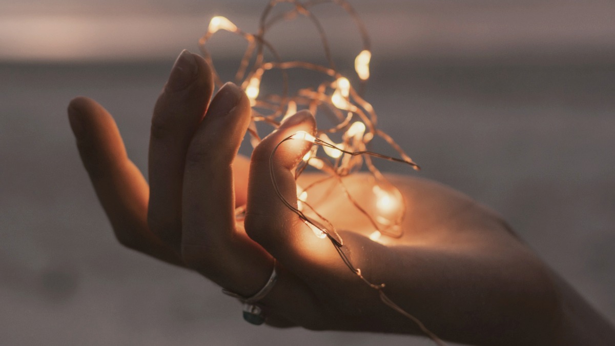 
selective focus photography of person holding lighted brown string light
