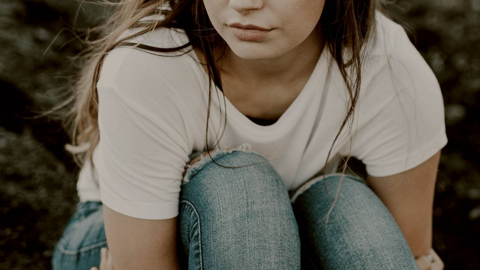 
shallow focus photo of person in white scoop-neck T-shirt hugging herself by Brooke Cagle
