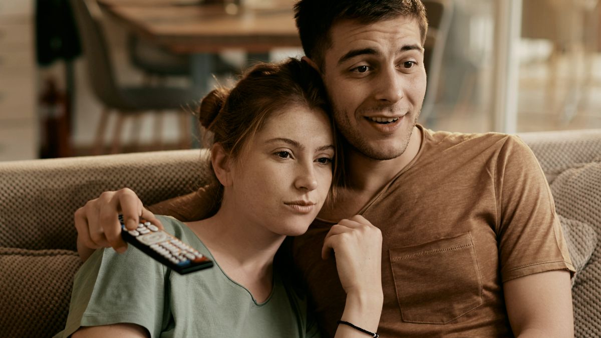 
Smiling couple watching Tv while relaxing on the sofa at home
