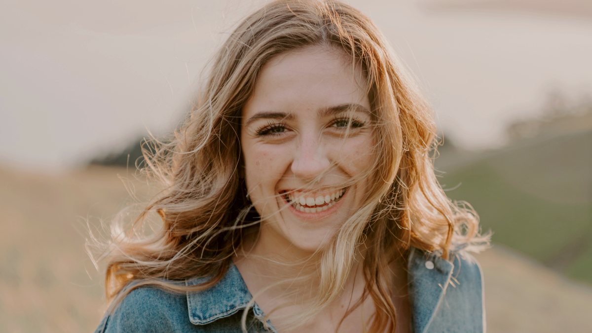 
smiling woman sitting on grass during daytime
