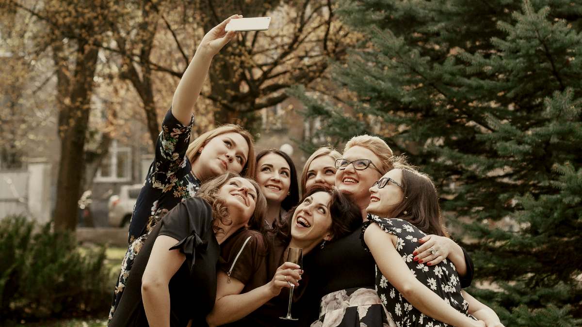 
stylish elegant women taking funny selfie at celebration sunny in park by getty images

