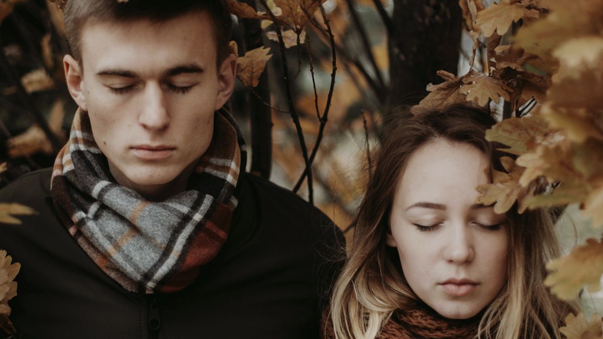 
stylish hipster couple posing under yellow leaves in autumn park
