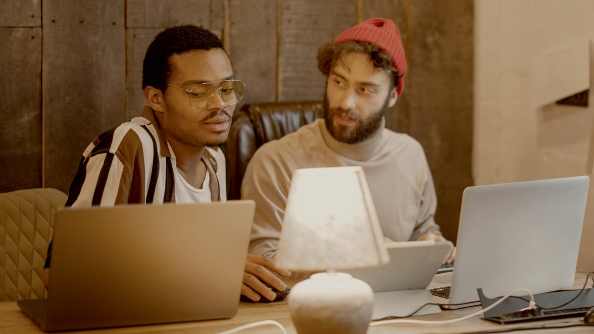 
Two men with different nationalities working on computers, sitting together in cozy home office. Stylish male hipsters programming together by Getty Images
