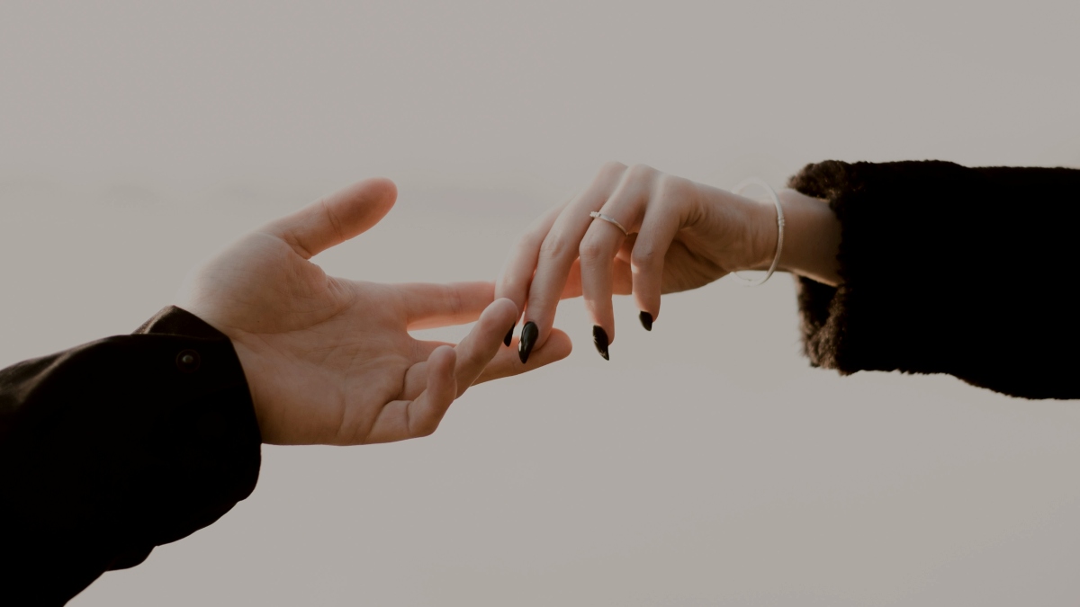 
two people reaching out their hands towards one another
