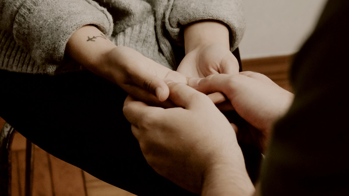 
two people sitting on a chairs facing each other holding hands by AC
