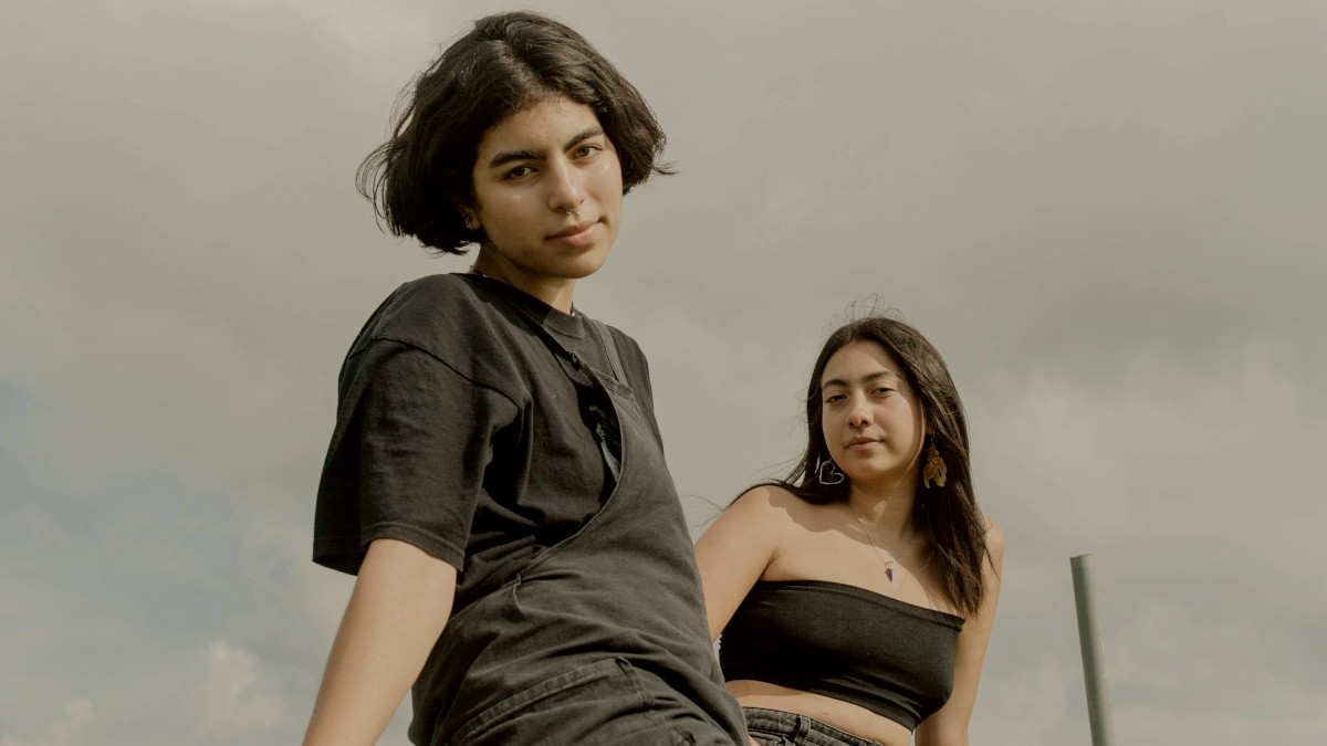 
Two sisters sitting on top of a cement wall
