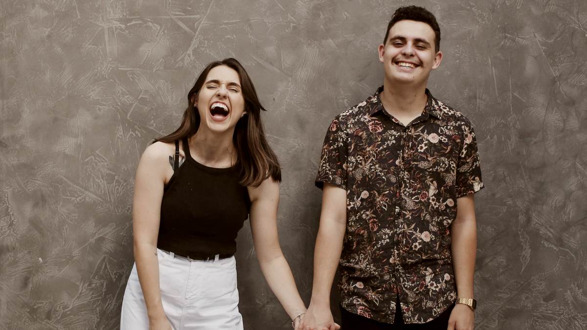 
woman and man holding in front of a textured grey wall
