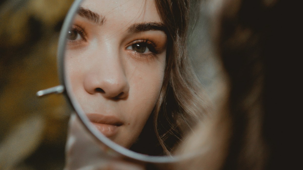 
woman holding a mirror up to her face
