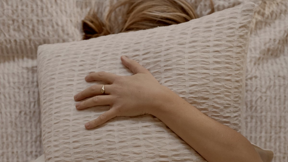 
Woman hugging a pillow in bed with white sheets by Karolina Grabowska
