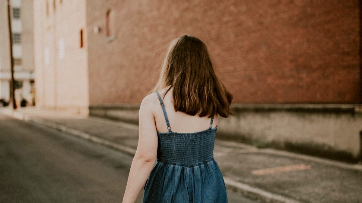 
woman in a teal spaghetti jumpsuit walking down the street by Hannah Busing
