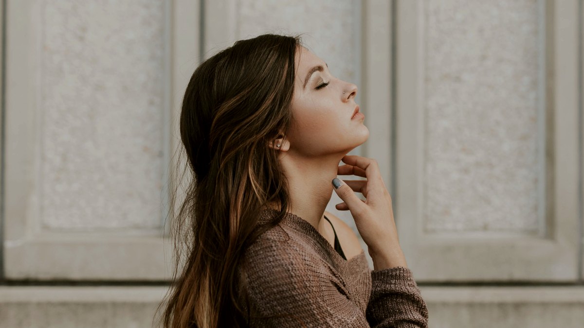 
woman in brown long-sleeved top standing beside wall
