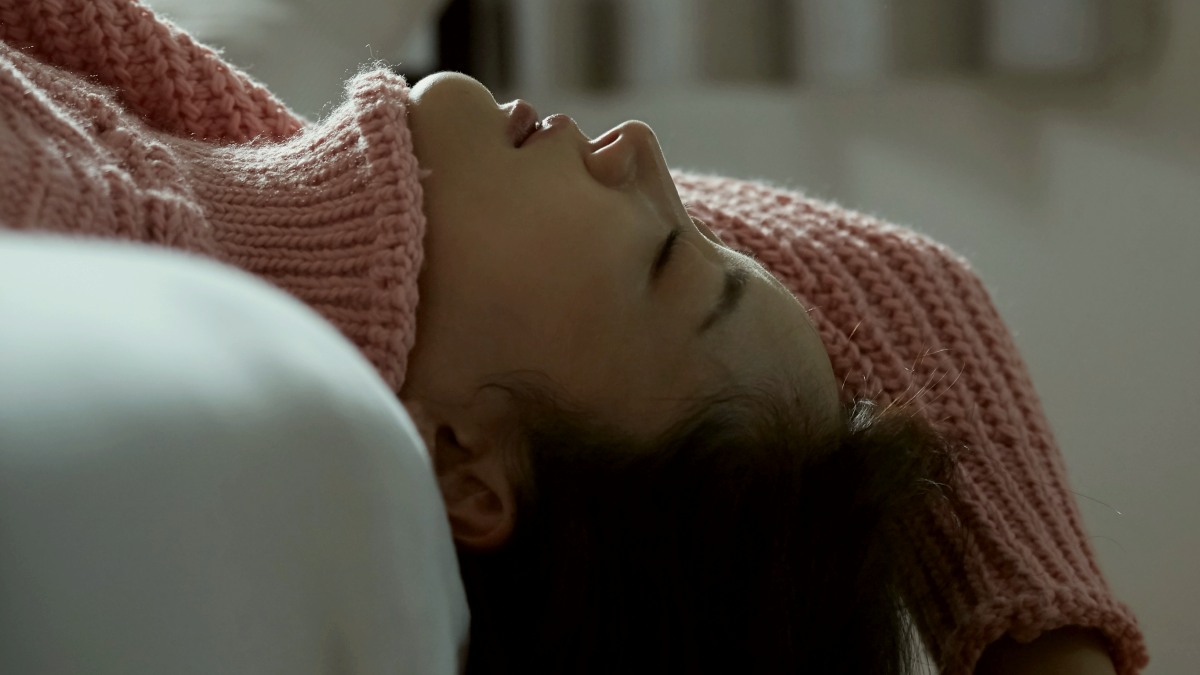 
woman in pink sweater laying off the side of a bed by getty images
