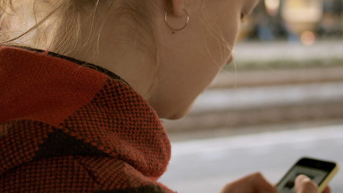 
woman in red flannel looking at her phone scrolling by Daria Nepriakhina
