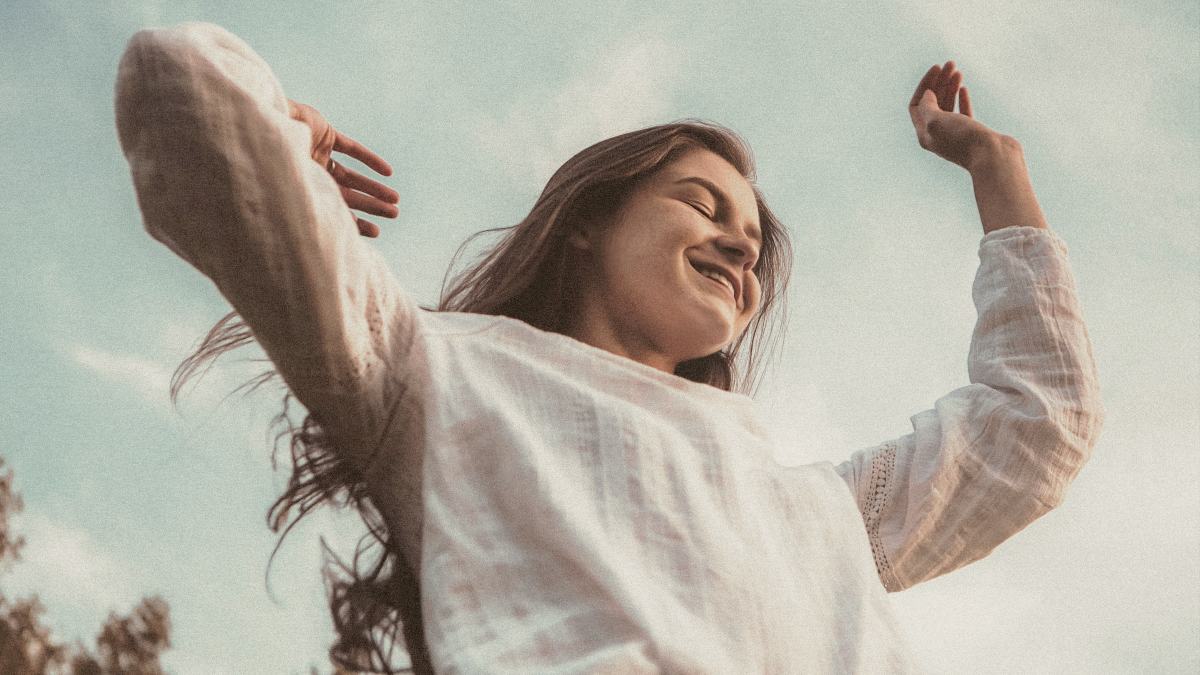 
woman in white long sleeve shirt and blue denim jeans outdoors with arms thrown skyward by Manny Moreno
