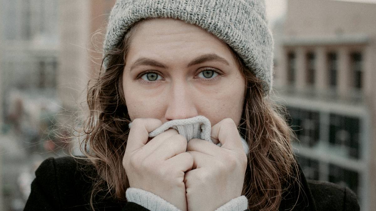 
woman on top of the building cringing into her sweater
