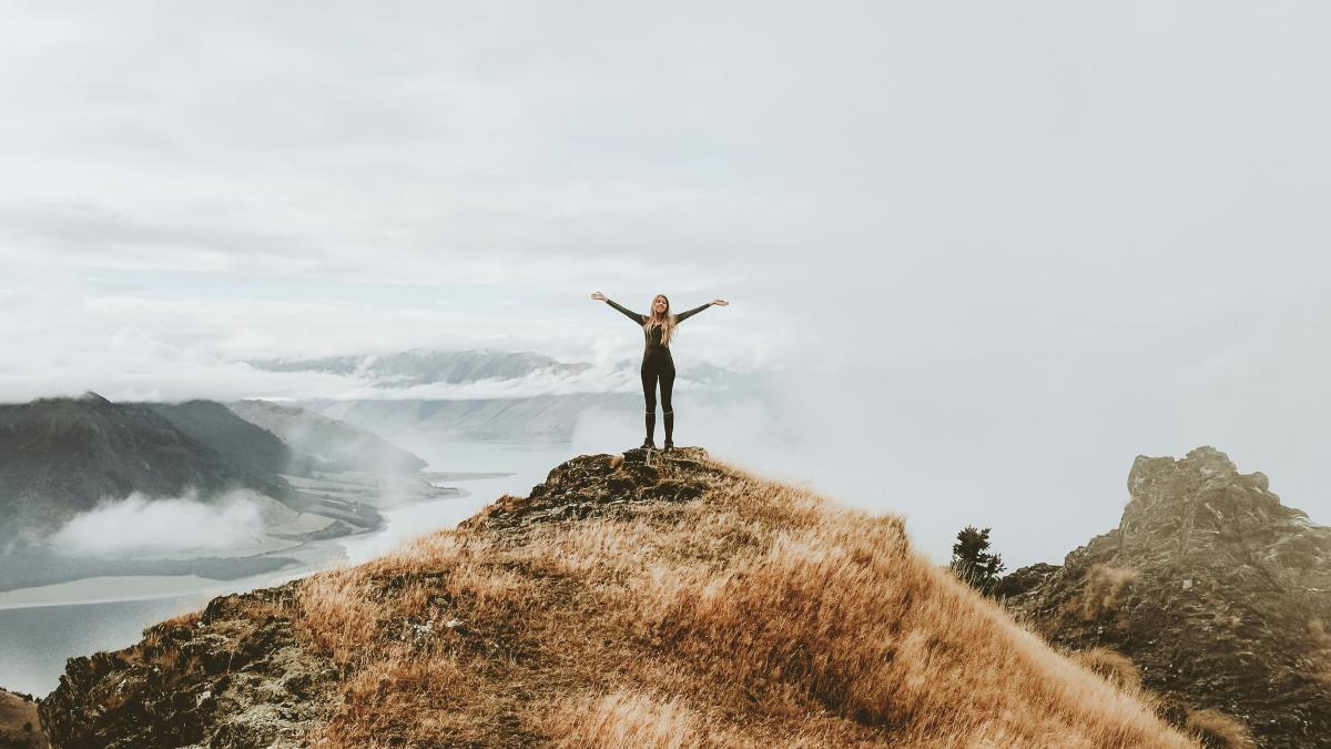 
woman standing on top of hill after a successful hike
