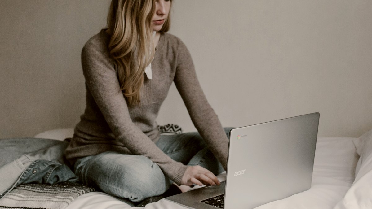 
woman-typing-on-macbook-pro-while-sitting-on-bed-in-room
