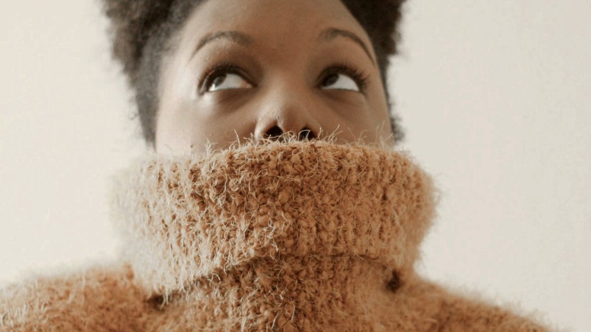 
woman wearing orange turtle neck sweat shirt looking upward
