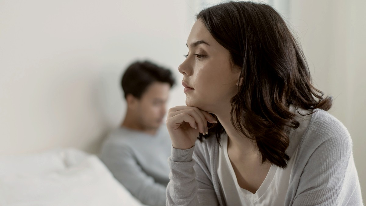 
young asian girl sitting on a bed feels angry at her boyfriend after having a domestic conflict
