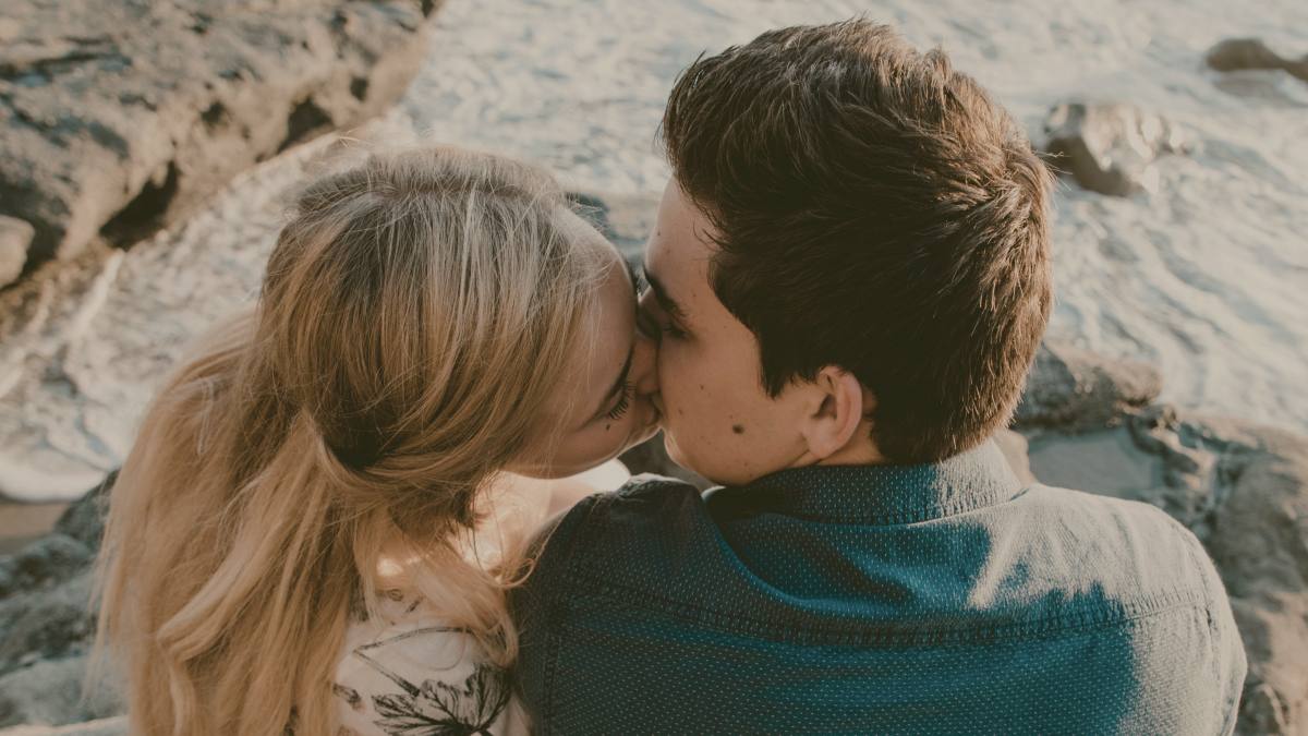 
young couple kissing white sitting on rock at the beach Edward Cisneros
