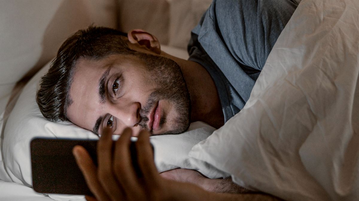 
Young man is lying in comfortable bed and texting on smart phone before falling asleep by getty images
